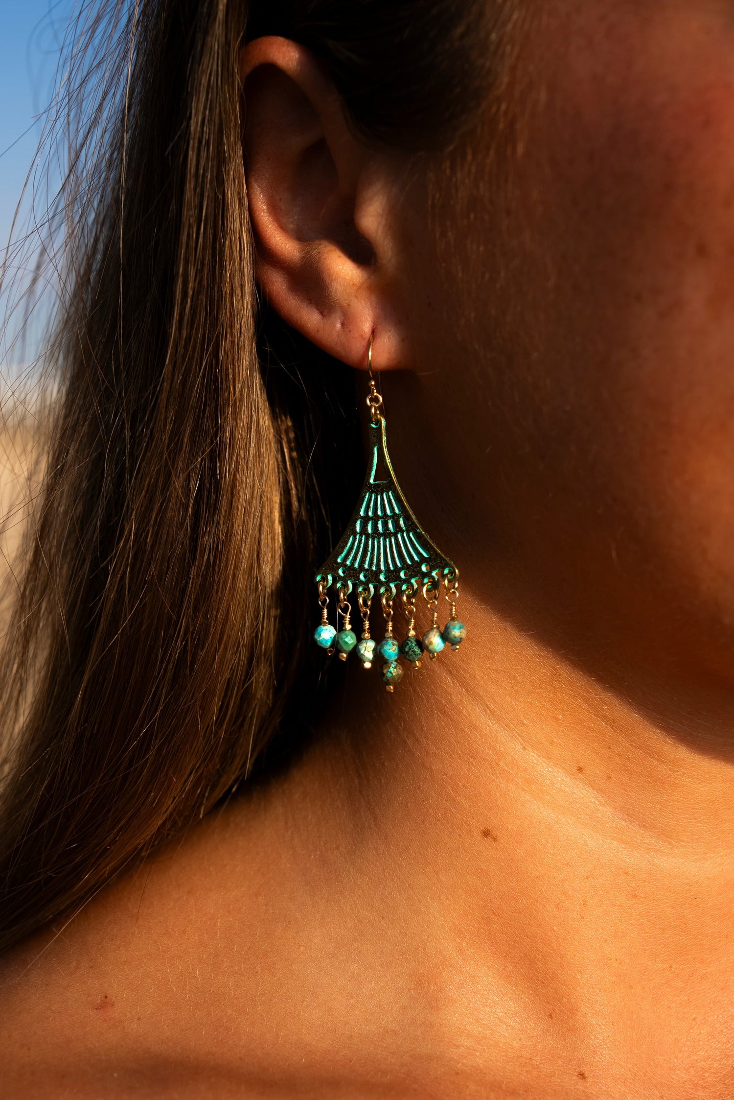 Young woman wearing a pair of Soul and Stone Patina Hand-Turned Gemstone Earrings.