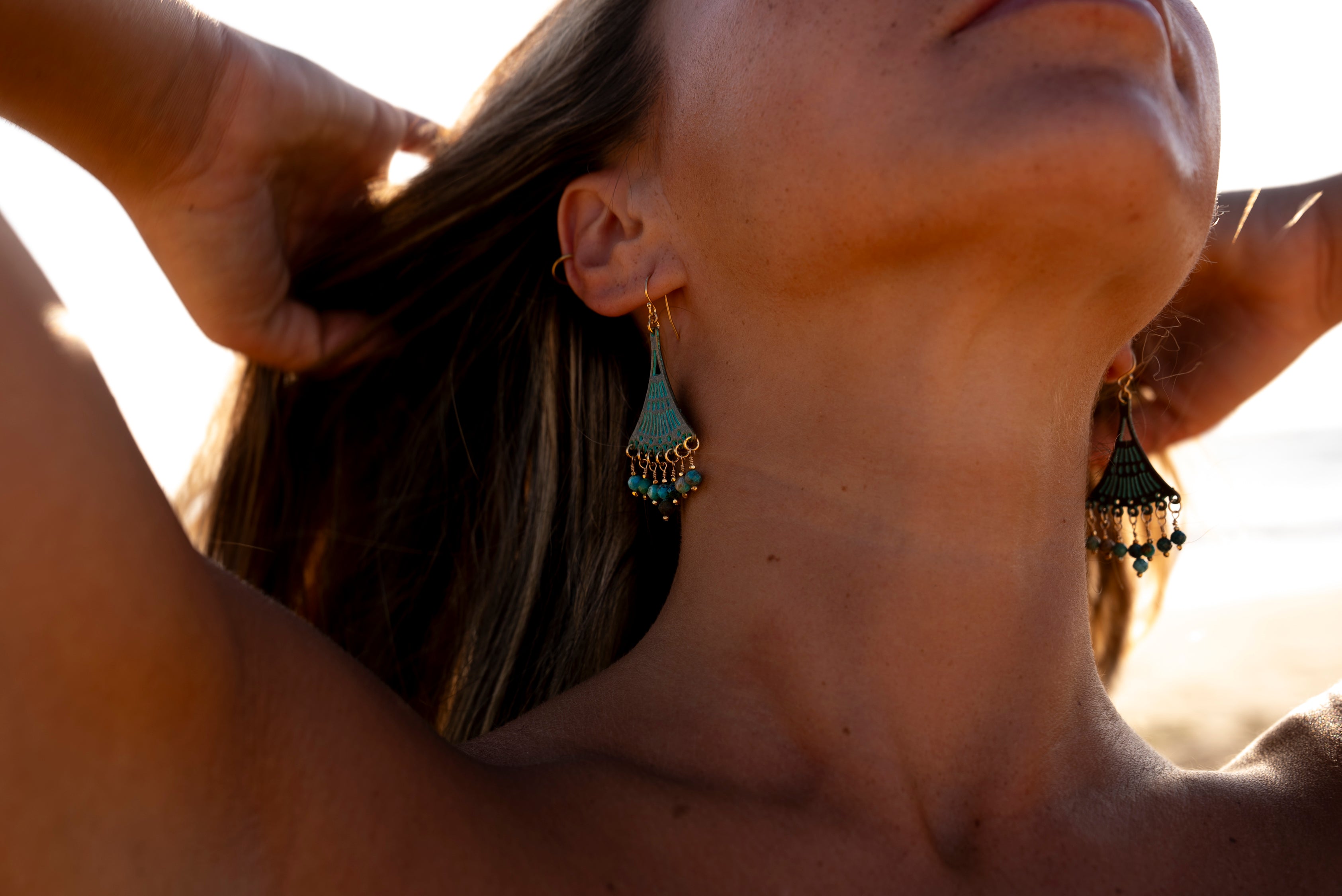 Young woman wearing a pair of Soul and Stone Patina Hand-Turned Gemstone Earrings, used as a banner for the 'Contact' page.